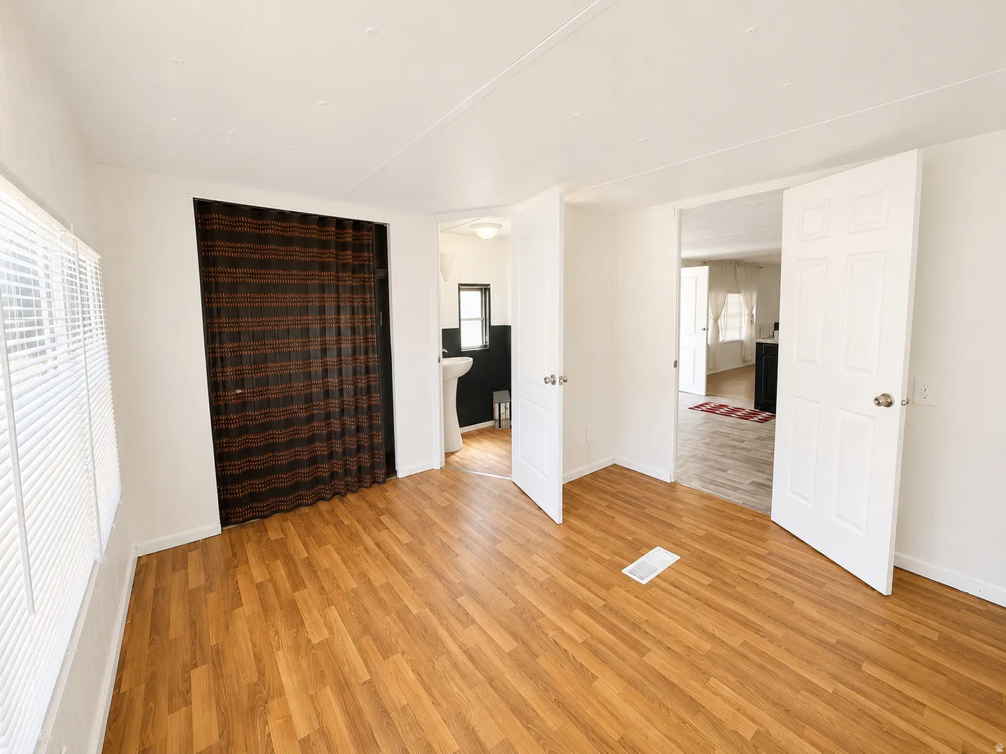 Bedroom with wood-look flooring, natural light, closet space, and convenient access to the adjoining bathroom and kitchen area.