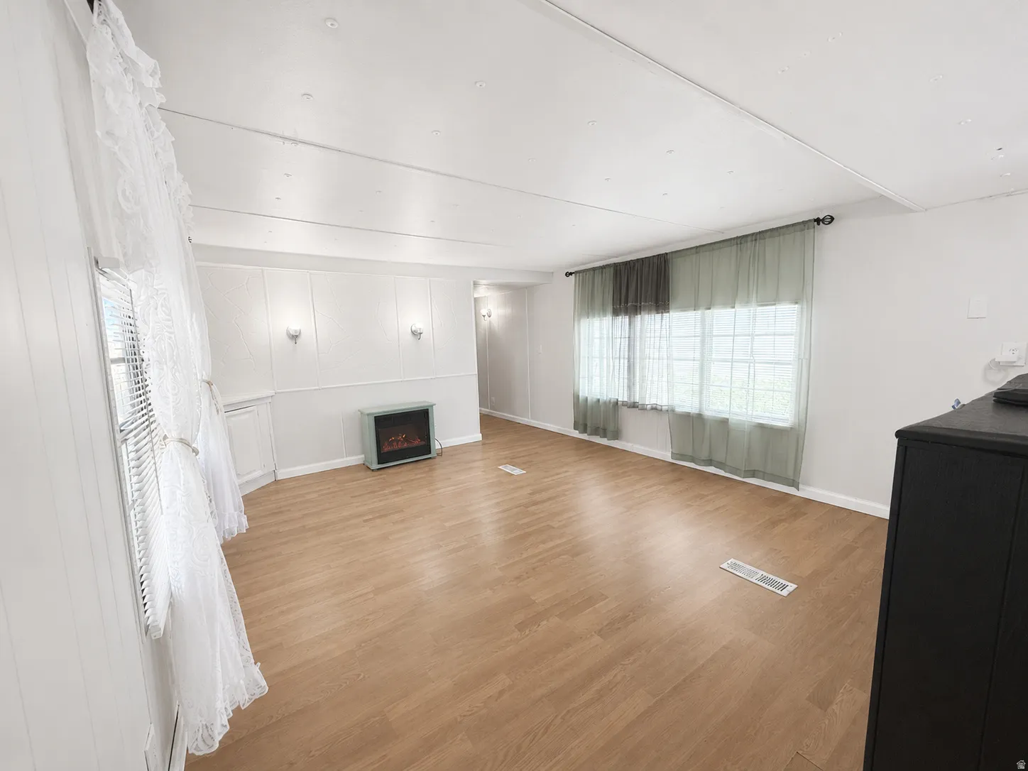 Alternate view of the living room showcasing the electric fireplace, large window, and flexible layout.