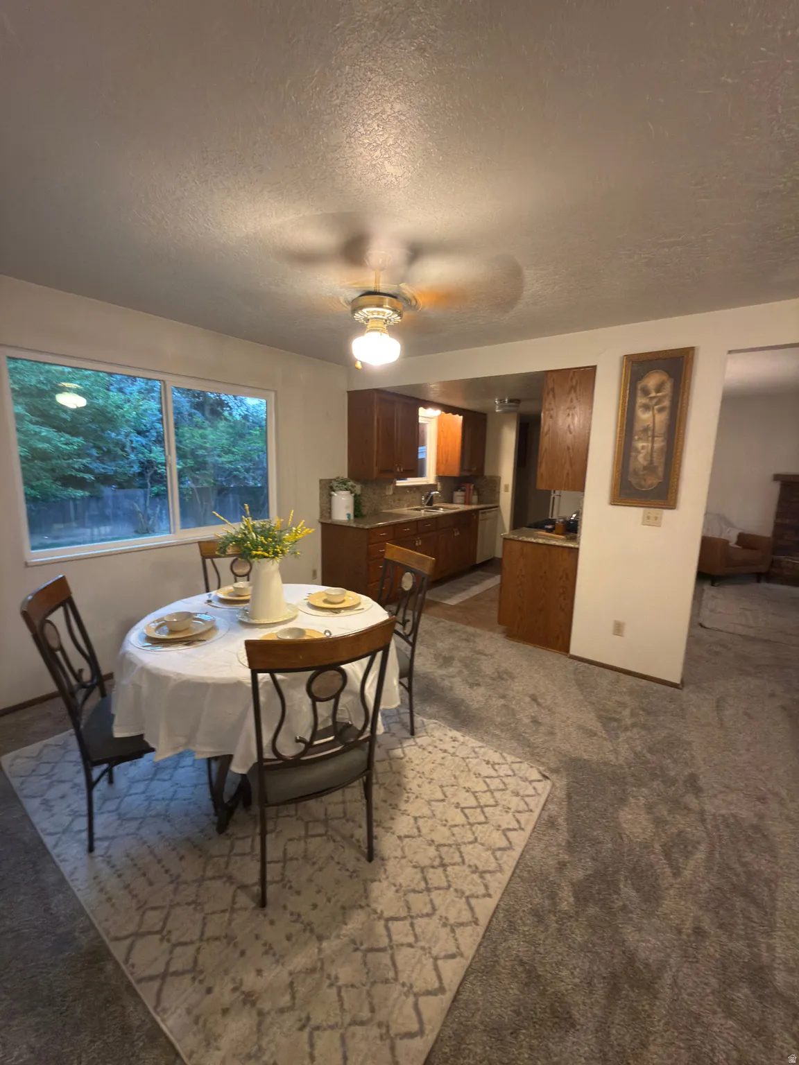 Dining area featuring carpet flooring, a large window, and a ceiling fan with integrated lighting