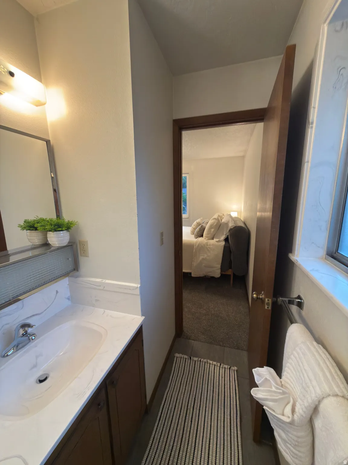 Bathroom vanity featuring a single basin sink, chrome faucet, and integrated countertop with a matching backsplash