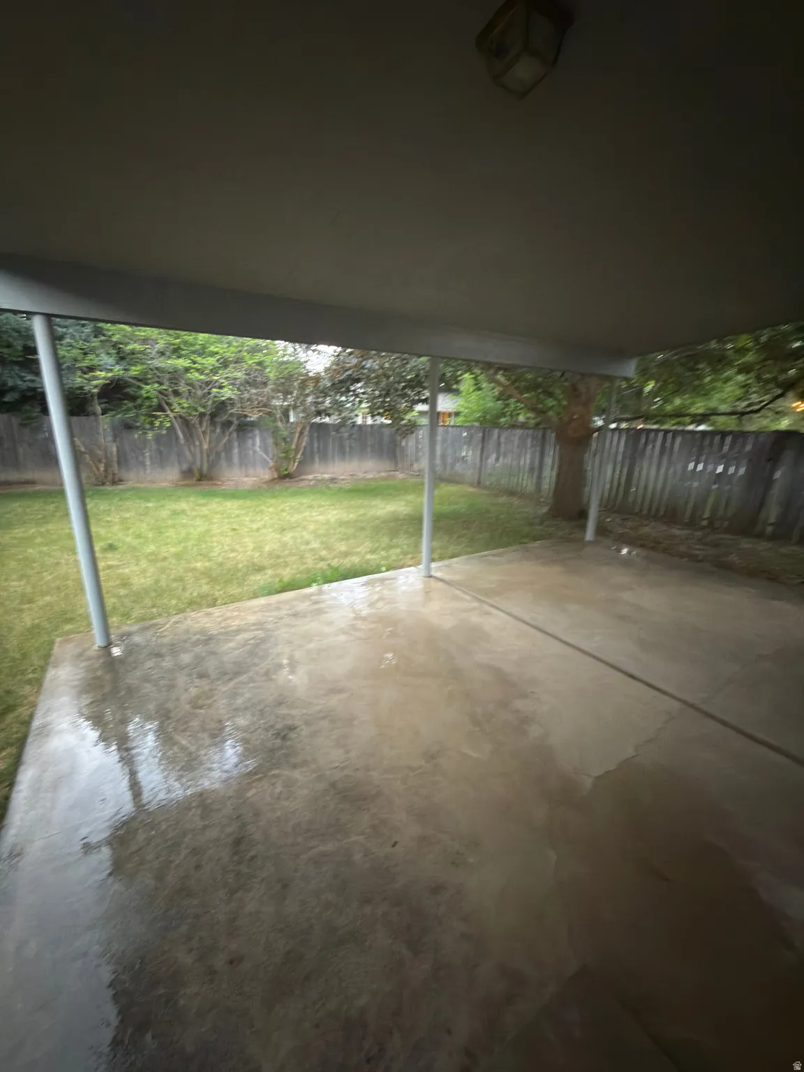 Covered patio with concrete flooring, supported by metal posts