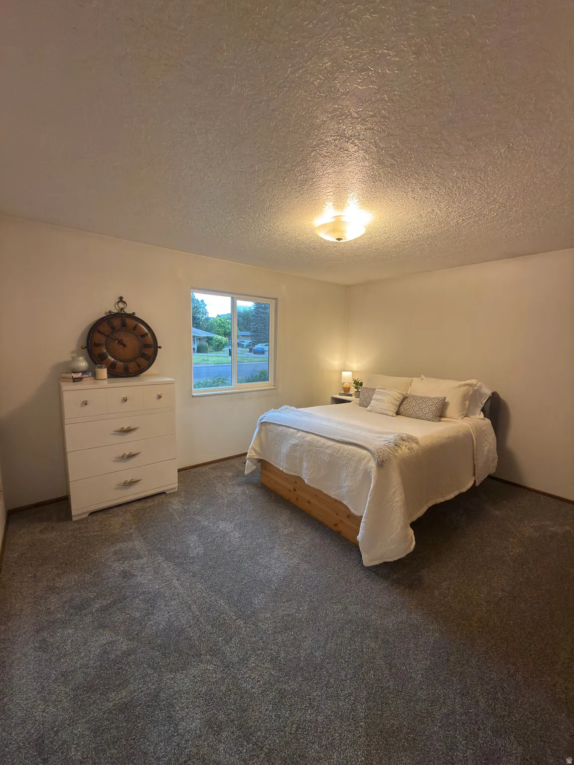 Bedroom featuring grey carpet, white walls, and a textured ceiling