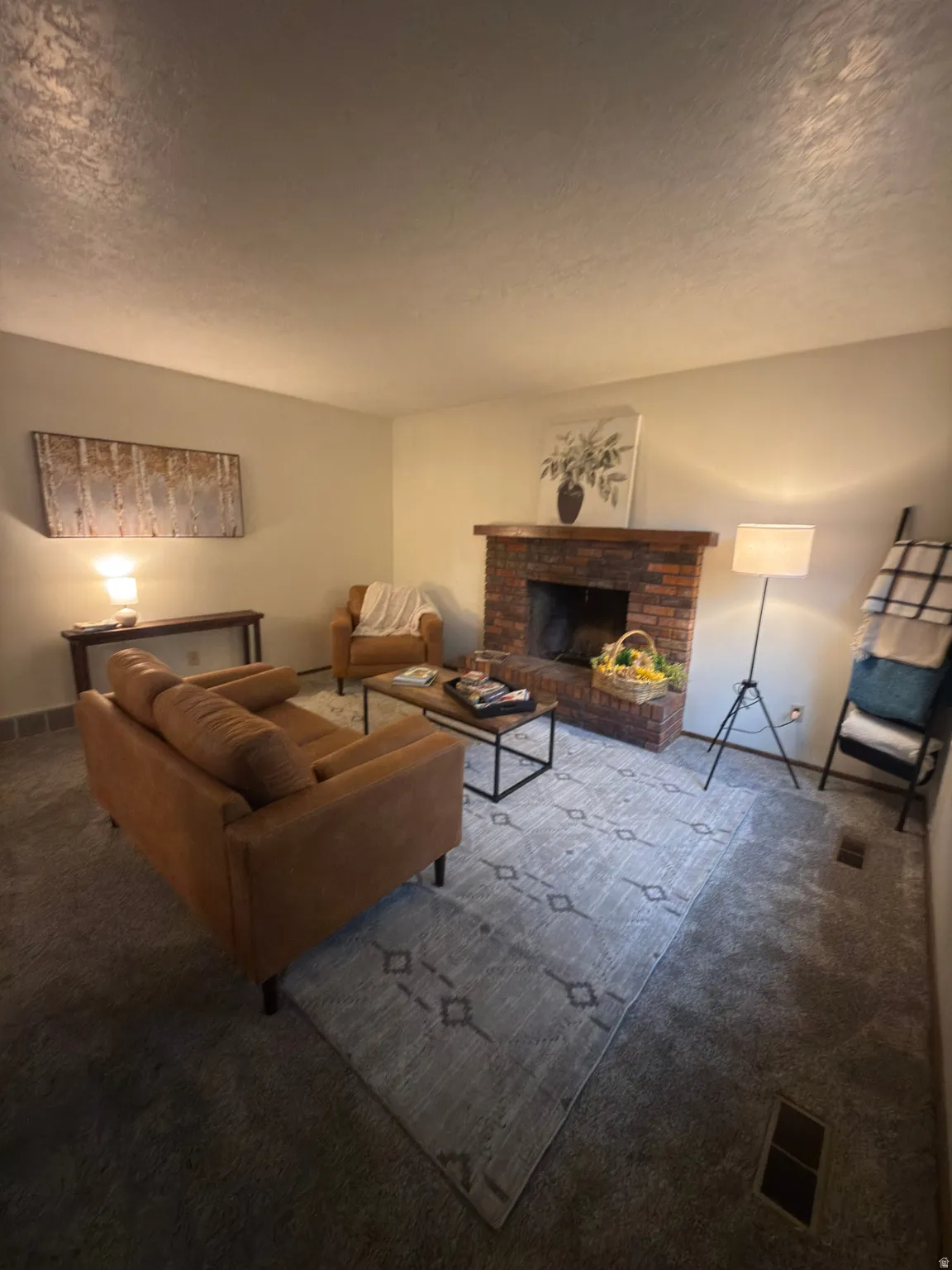 Living area featuring a brick fireplace with a wood mantle, neutral wall colors, and carpet flooring