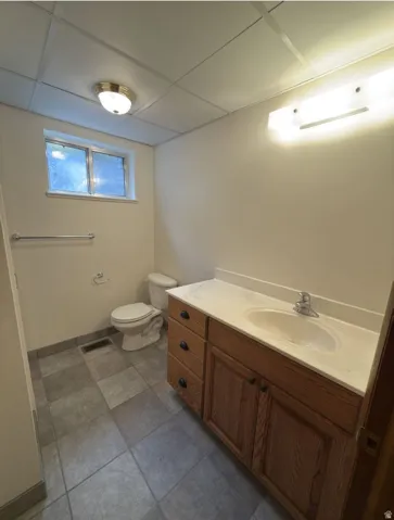 Bathroom featuring a wood-finish vanity with a built-in sink and countertop, complemented by a wall-mounted light fixture