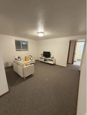 Spacious room featuring carpeting, a single window with blinds, and a ceiling-mounted light fixture