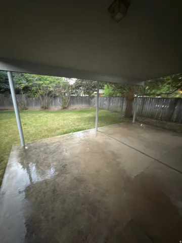 Covered patio with concrete flooring, supported by metal posts