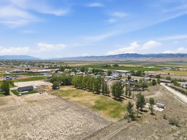 Expansive land parcel featuring open fields, distant mountain ranges, and numerous mature trees