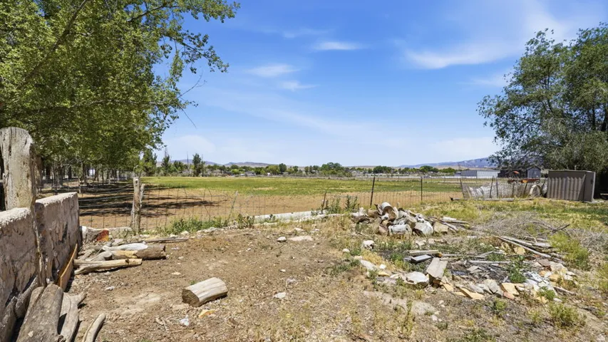 Expansive land parcel featuring existing fencing, mature trees, and distant mountain ranges