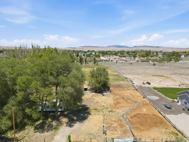 Expansive property featuring multiple fenced areas, mature trees, and a distant townscape
