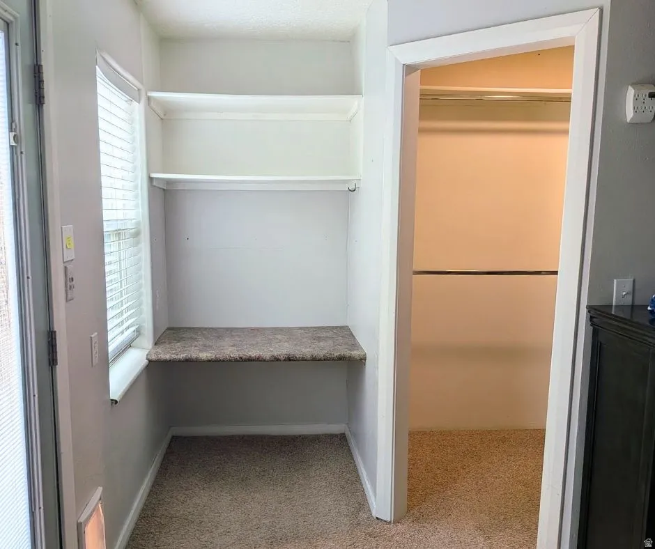 Dedicated alcove featuring a built-in countertop, integrated shelving, and carpet flooring