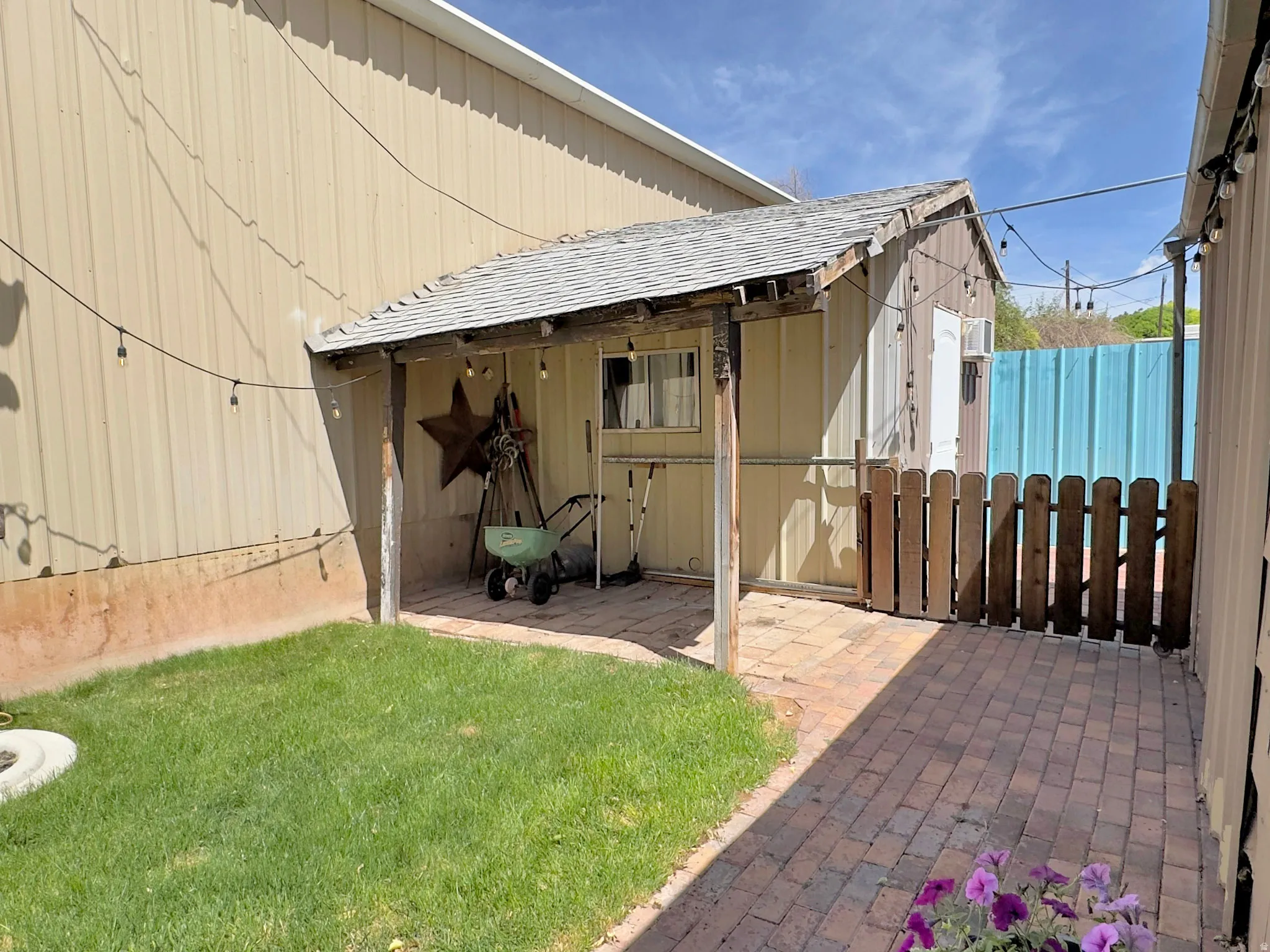 Expansive outdoor area featuring a brick paver patio, a partial lawn, and a wooden fence