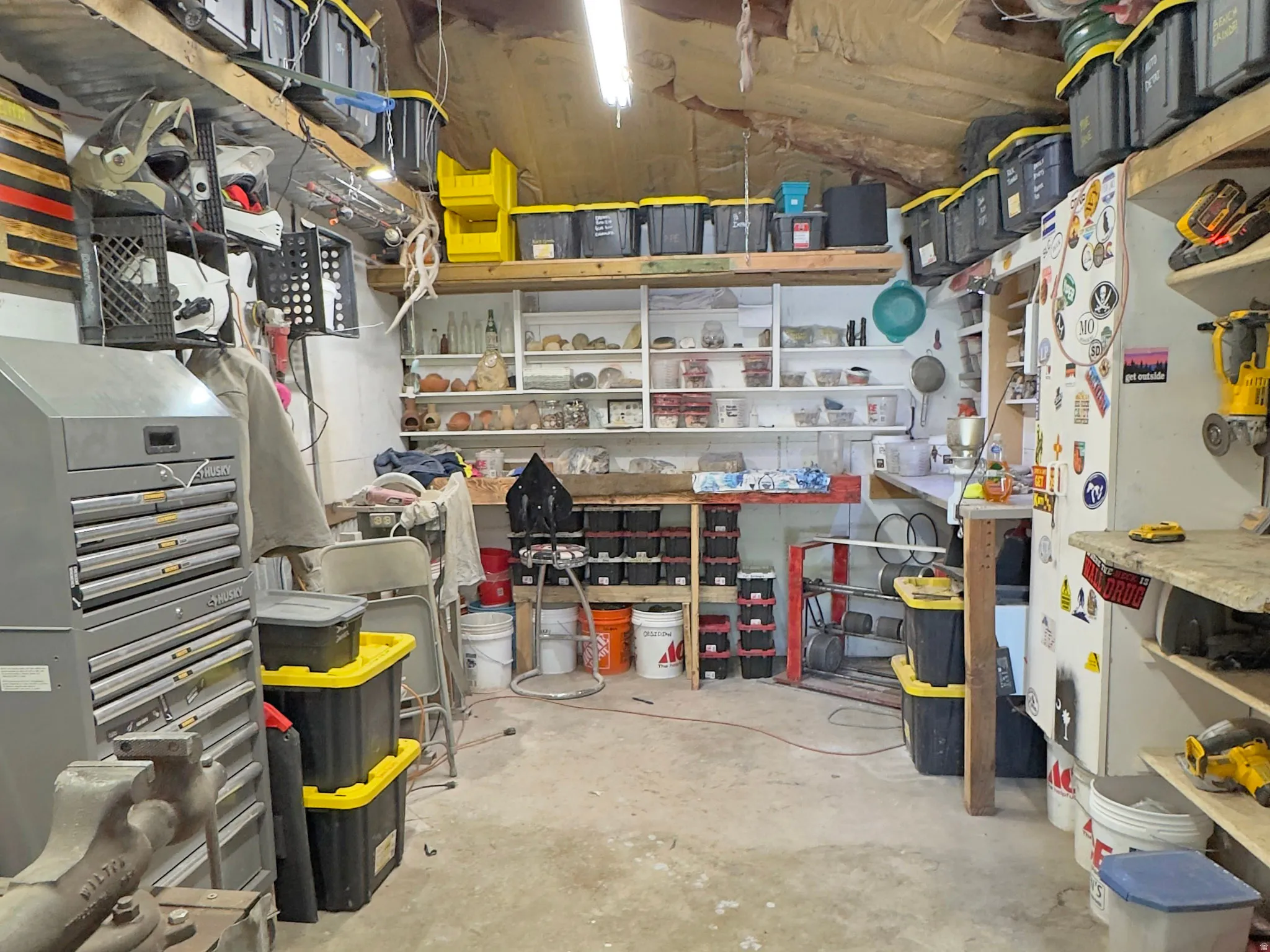 Utility space with built-in shelving, concrete flooring, and overhead lighting