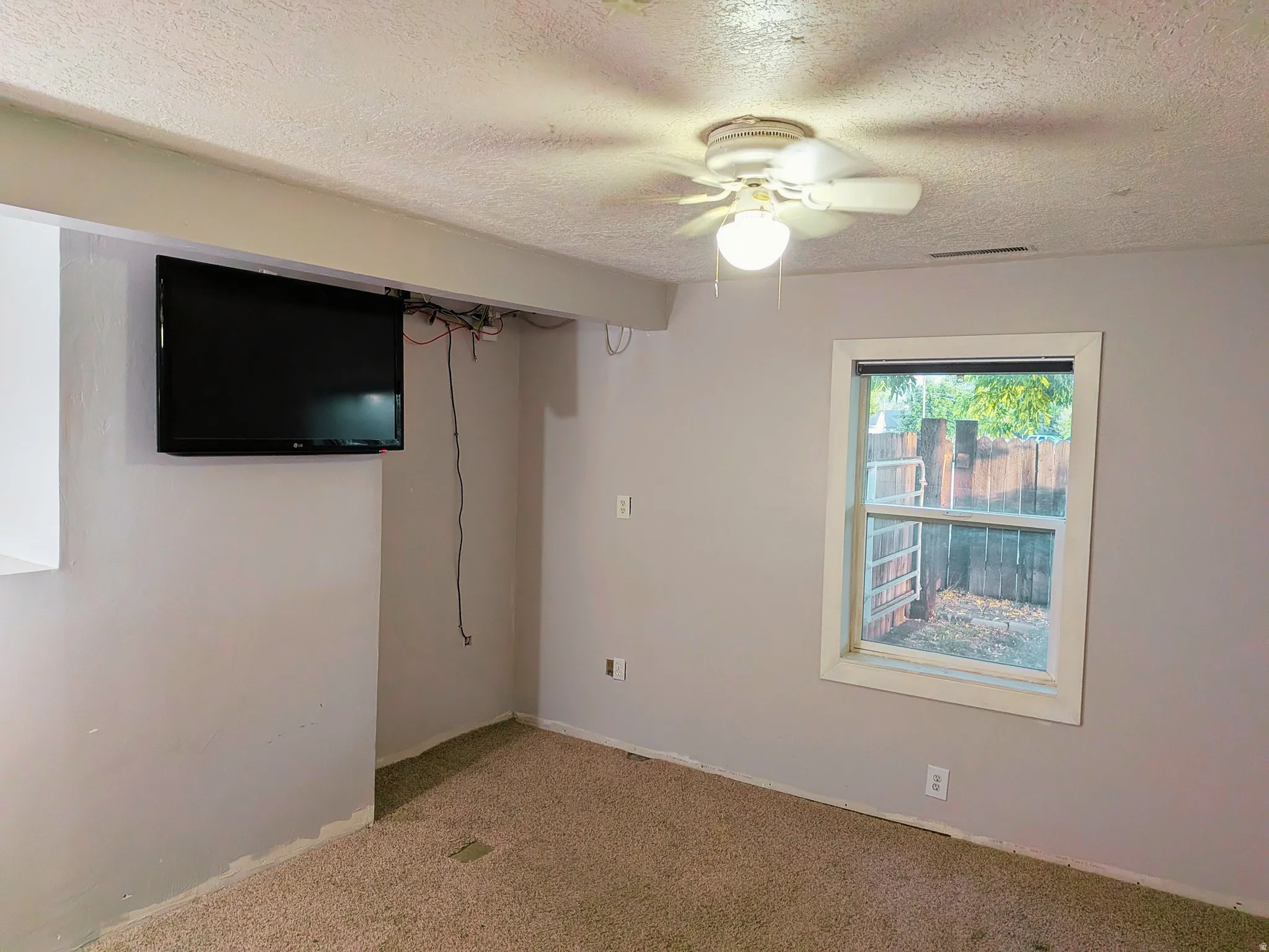 Carpeted interior space with a ceiling fan, a window, and light-toned walls