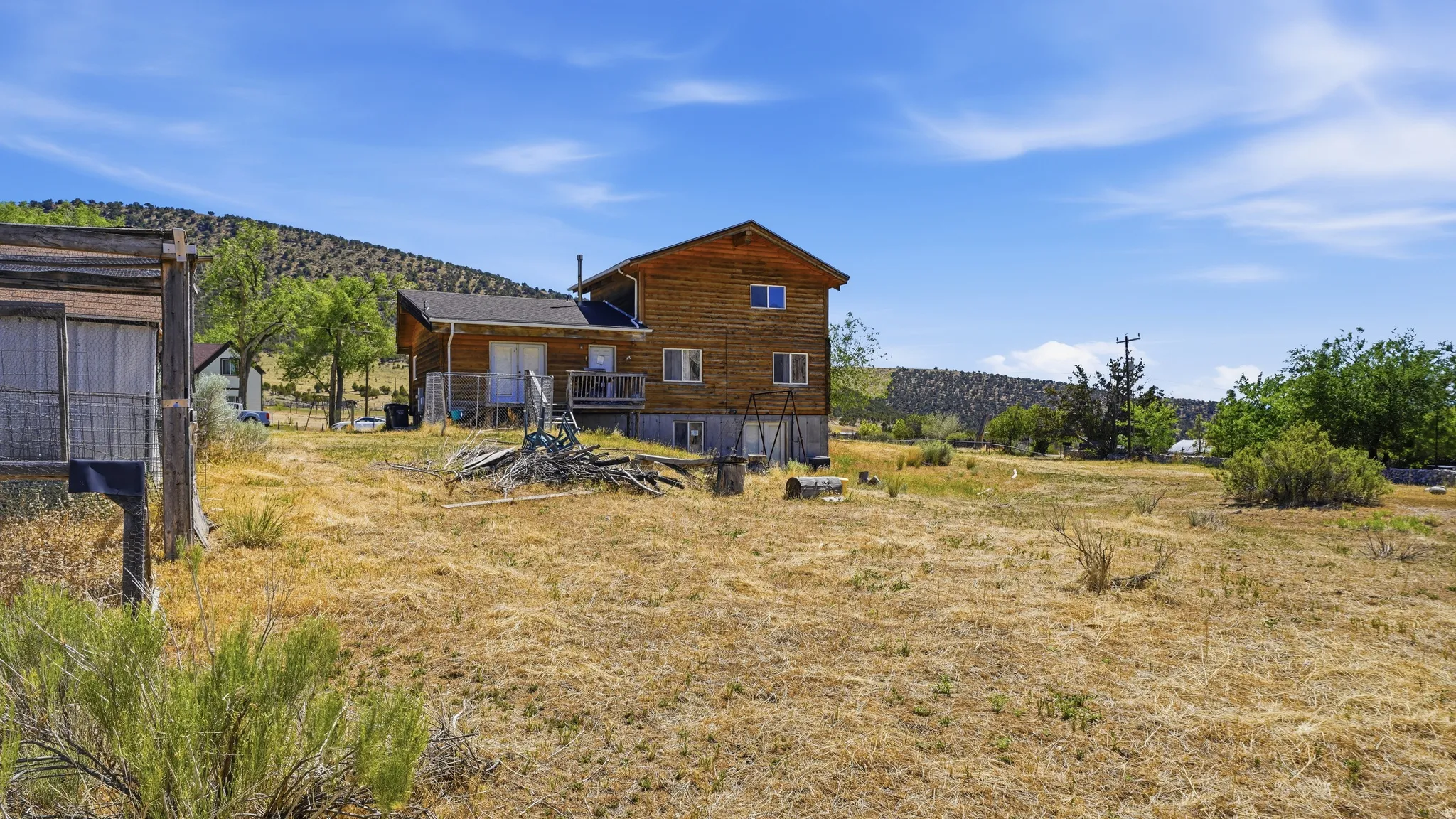 Two-story wood-sided cabin with multiple windows and an elevated rear deck