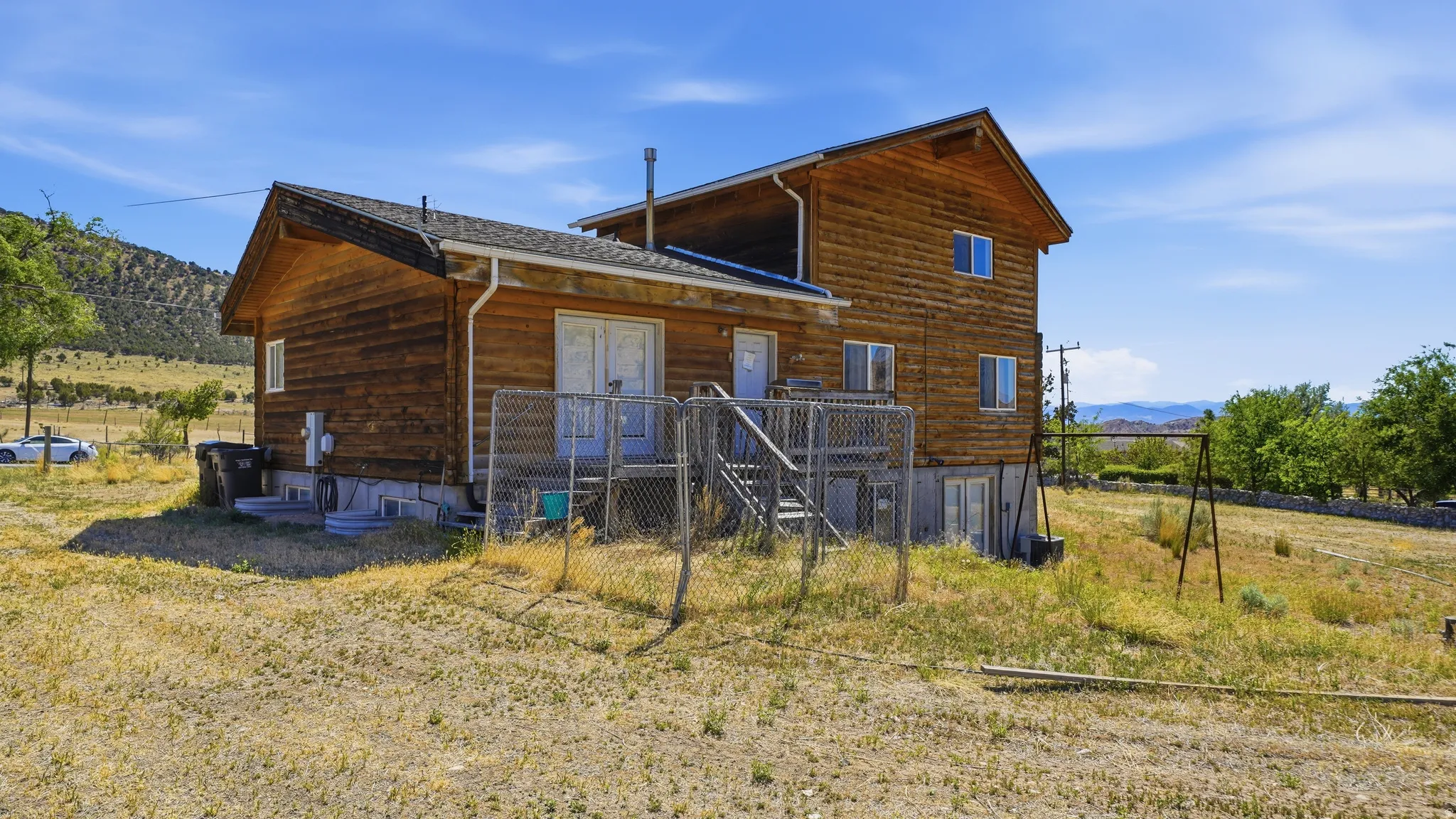 Two-story wood-sided cabin with a gabled roofline and white window frames