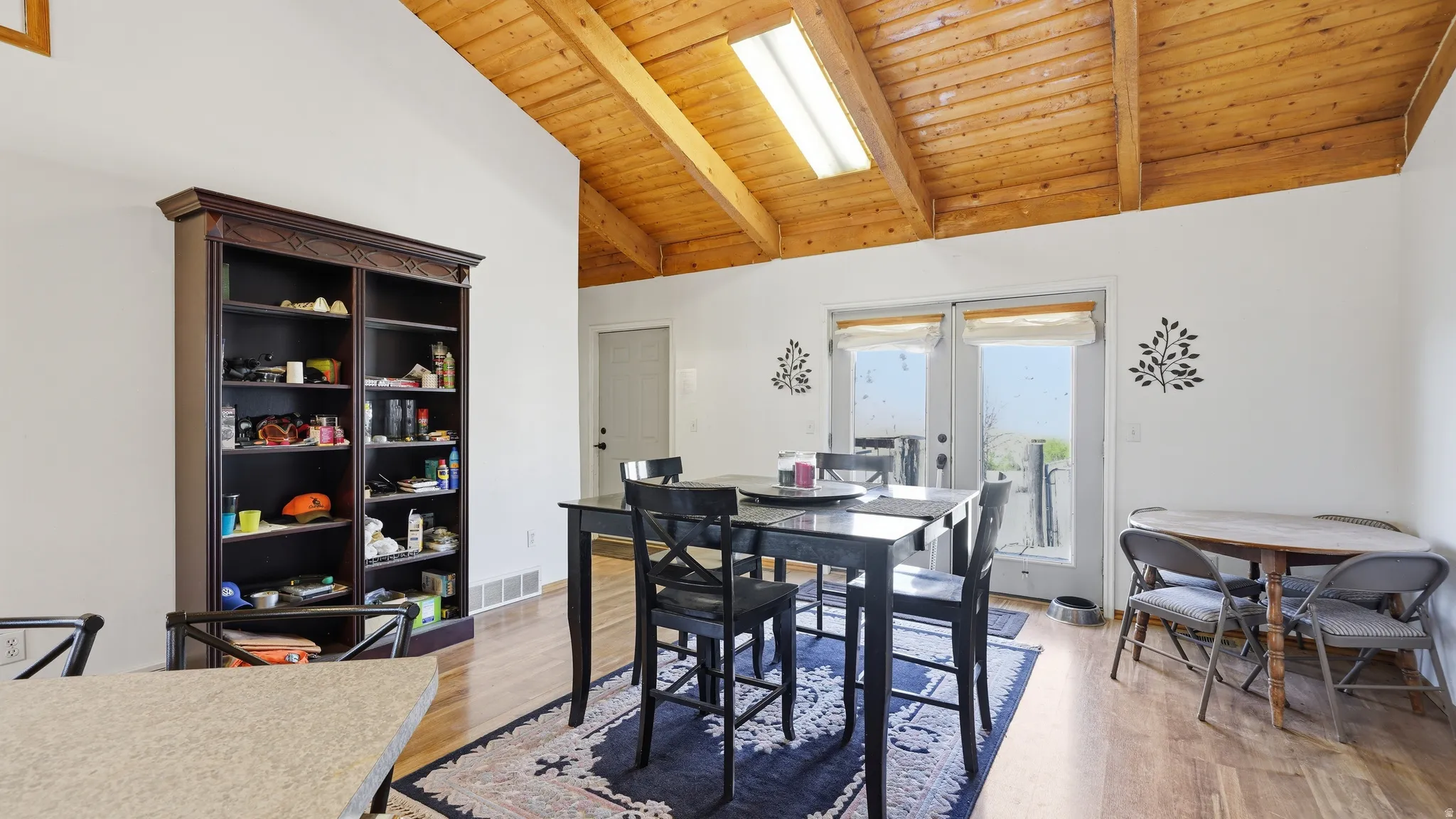 Dining area with a natural wood vaulted ceiling, exposed beams, and a skylight