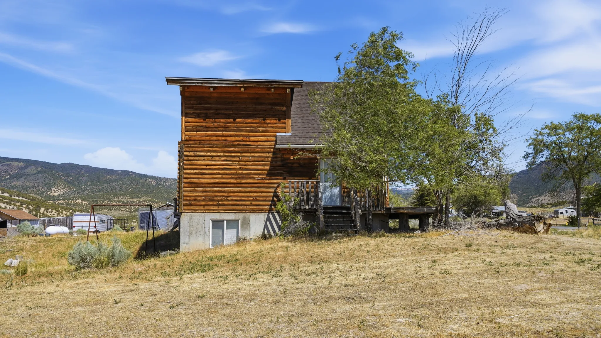 Log-sided home featuring a gabled roofline and a concrete foundation