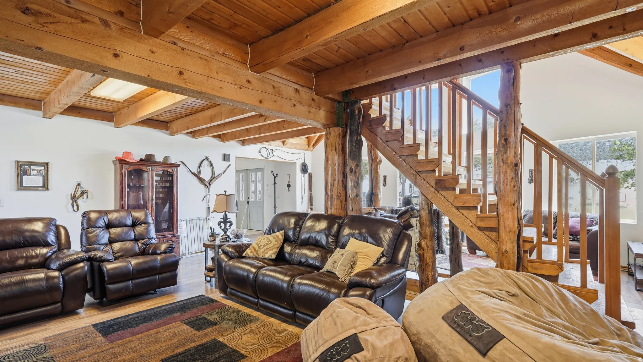 Spacious interior featuring exposed wood beam ceilings and a prominent wood staircase