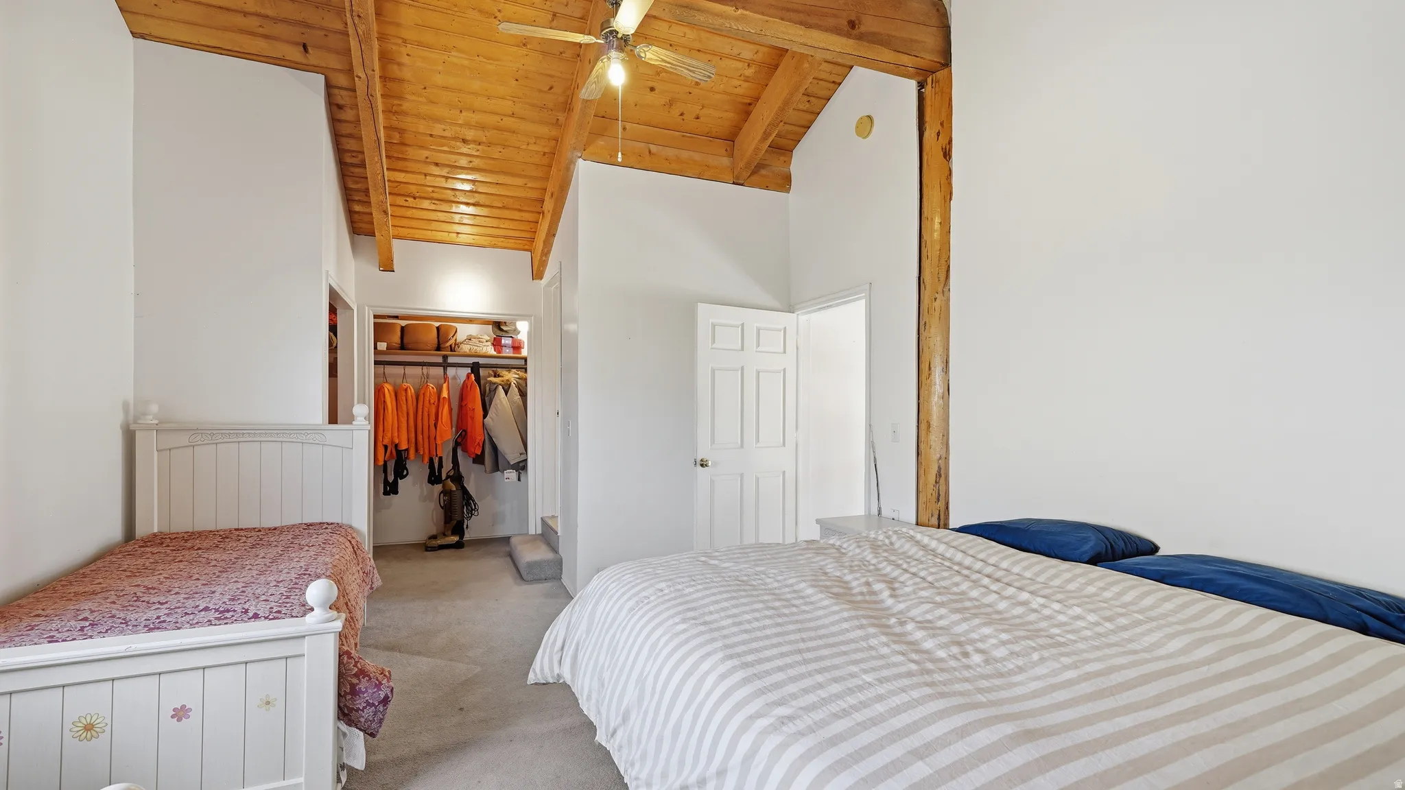 Vaulted wood-paneled ceiling with exposed wood beams, featuring a ceiling fan