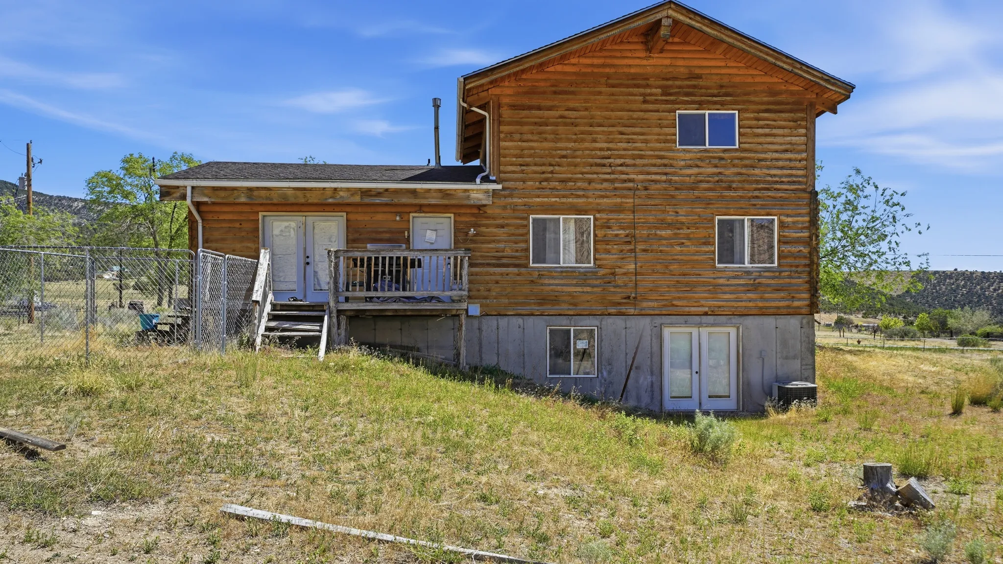Log-style exterior with a wood deck and fenced area