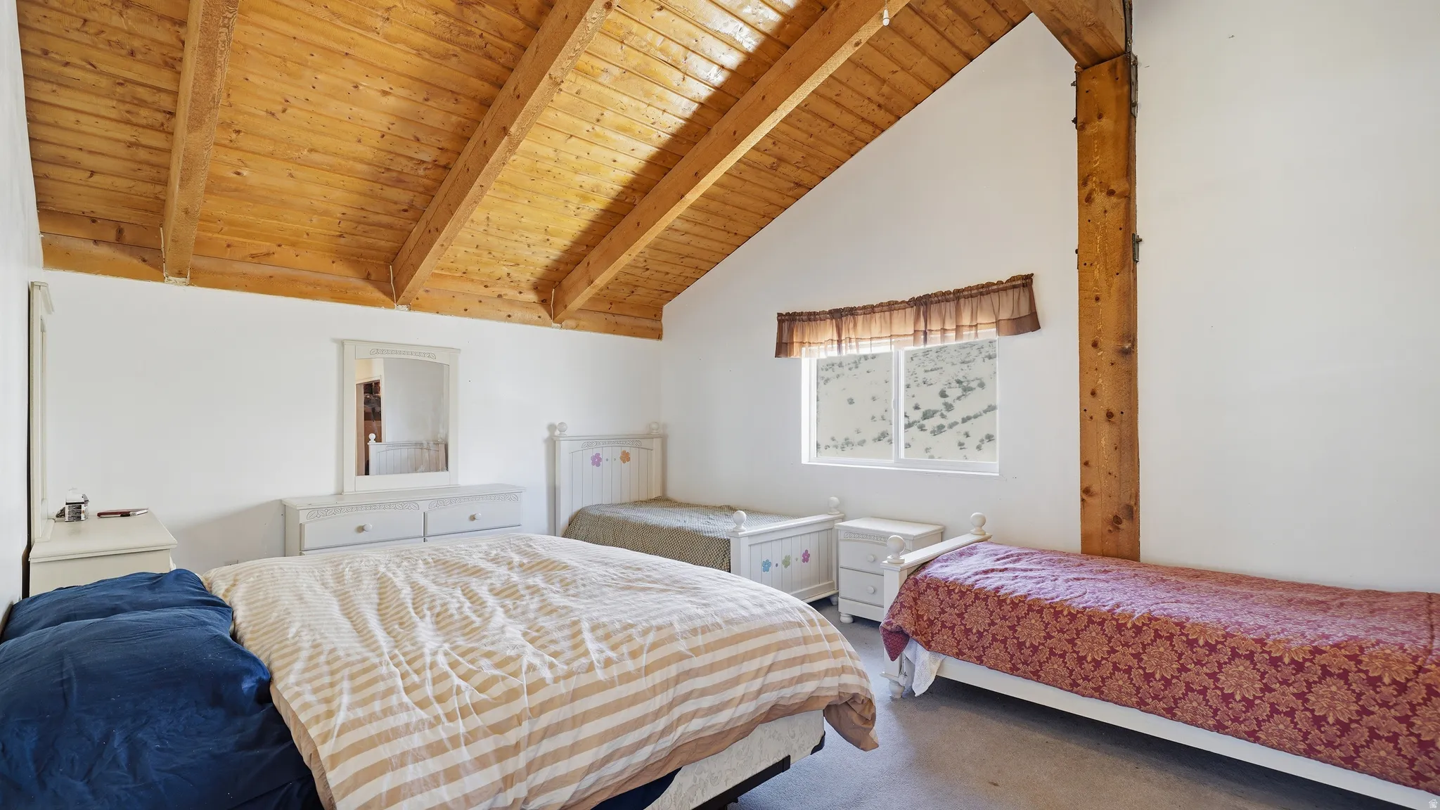 Vaulted wood-plank ceilings with exposed beams, white painted walls, and a single window with window treatments
