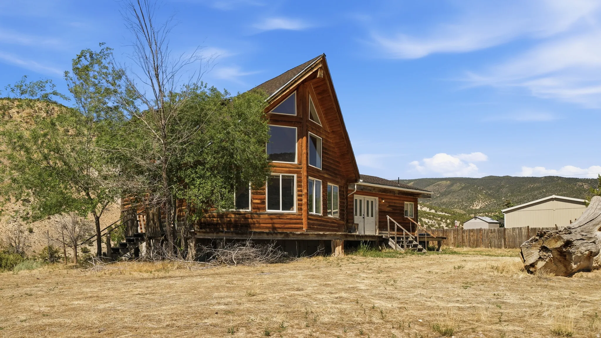 Rustic log-sided structure featuring a prominent A-frame design with a full wall of windows