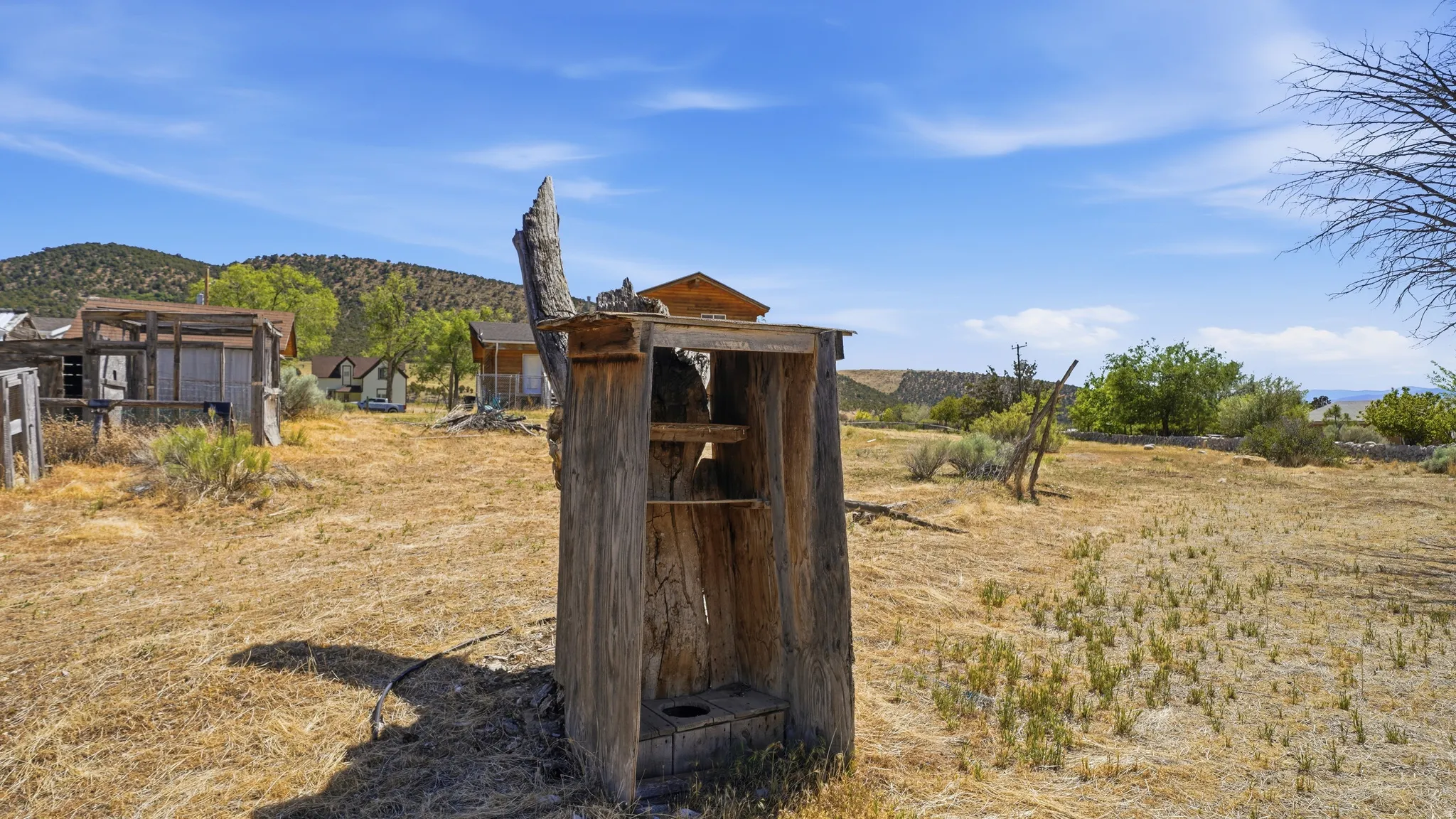 Weathered wood outhouse structure with a dry grass landscape