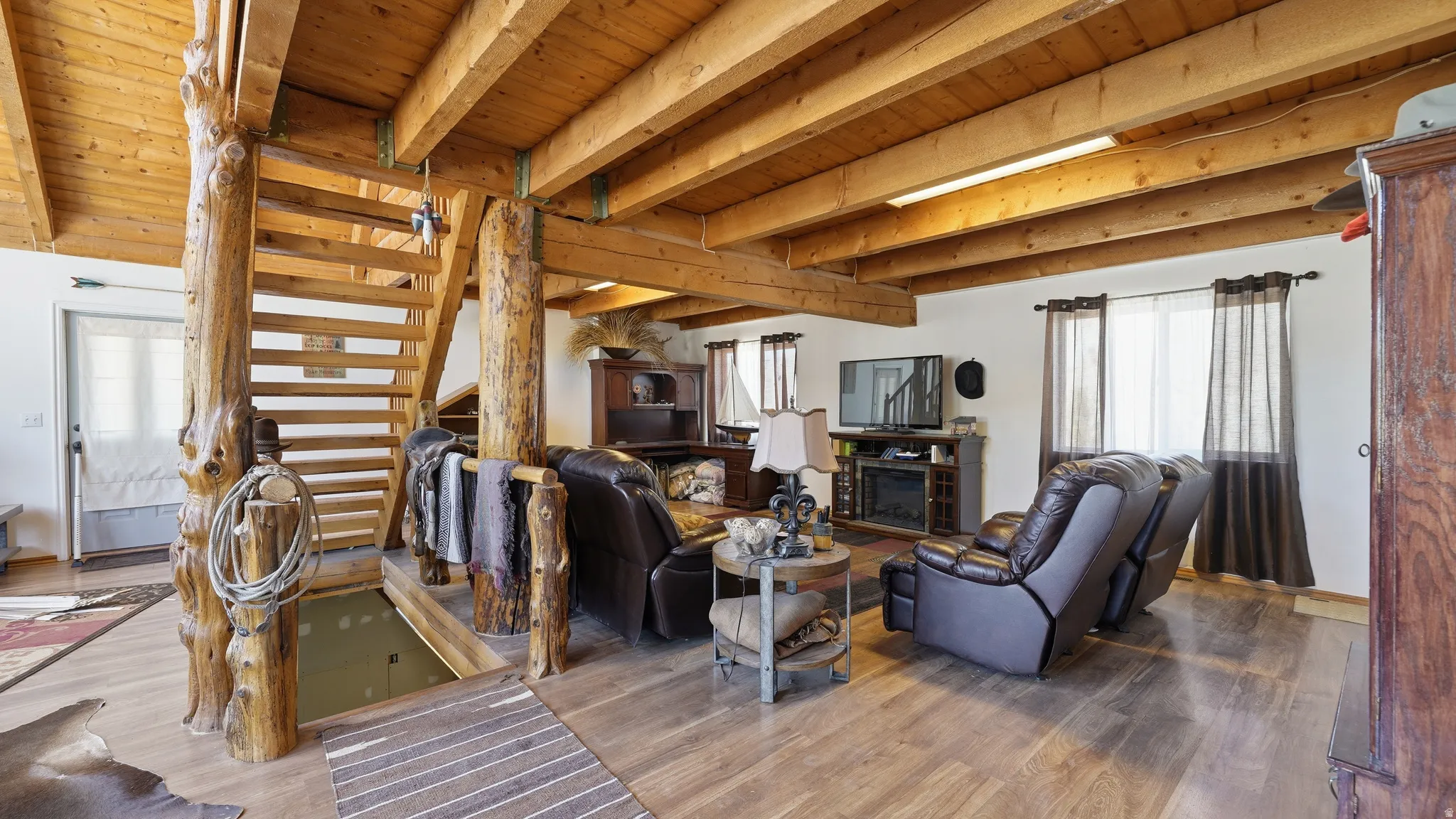 Natural wood staircase with log posts and open risers, complementing exposed wood ceiling beams