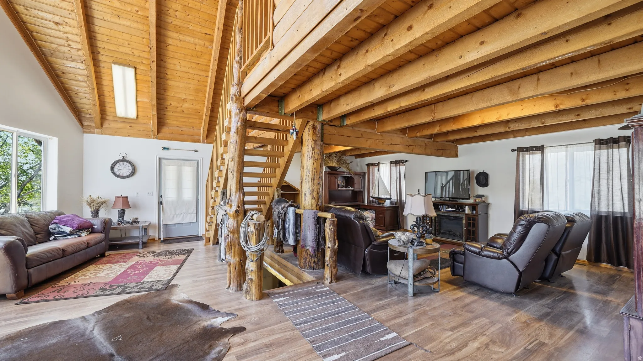 Open-concept living space featuring exposed wood beams and a vaulted ceiling with a skylight