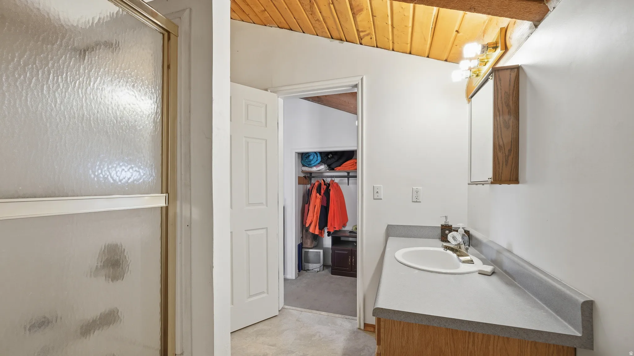 Bathroom vanity with a white basin sink, gray countertop, and wood-finish cabinetry