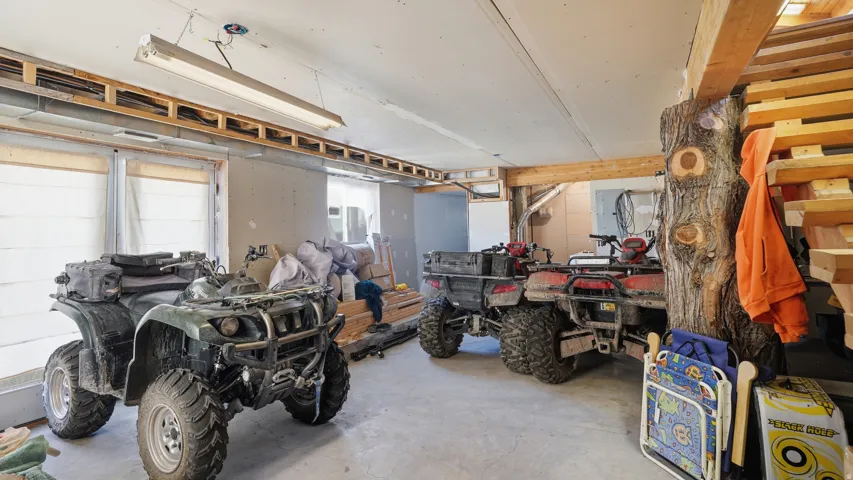 Utility space featuring concrete flooring, exposed wood beams, and a fluorescent light fixture