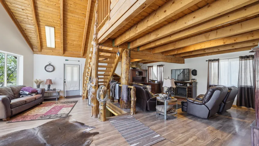 Open-concept living space featuring exposed wood beams and a vaulted ceiling with a skylight