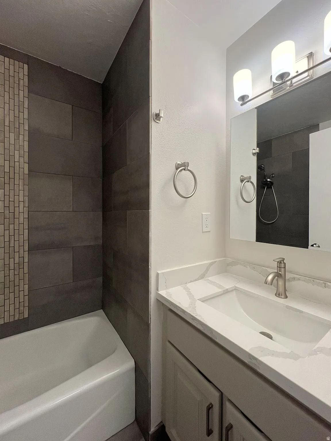 Bathroom vanity with a white rectangular undermount sink, a stone-finish countertop, and a brushed nickel single-handle faucet