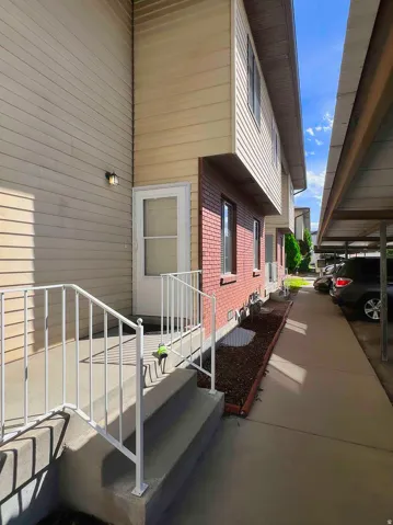 Entryway with concrete steps, white metal handrails, and a stucco exterior