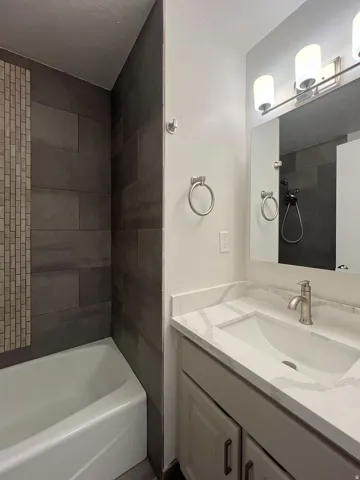 Bathroom vanity with a white rectangular undermount sink, a stone-finish countertop, and a brushed nickel single-handle faucet