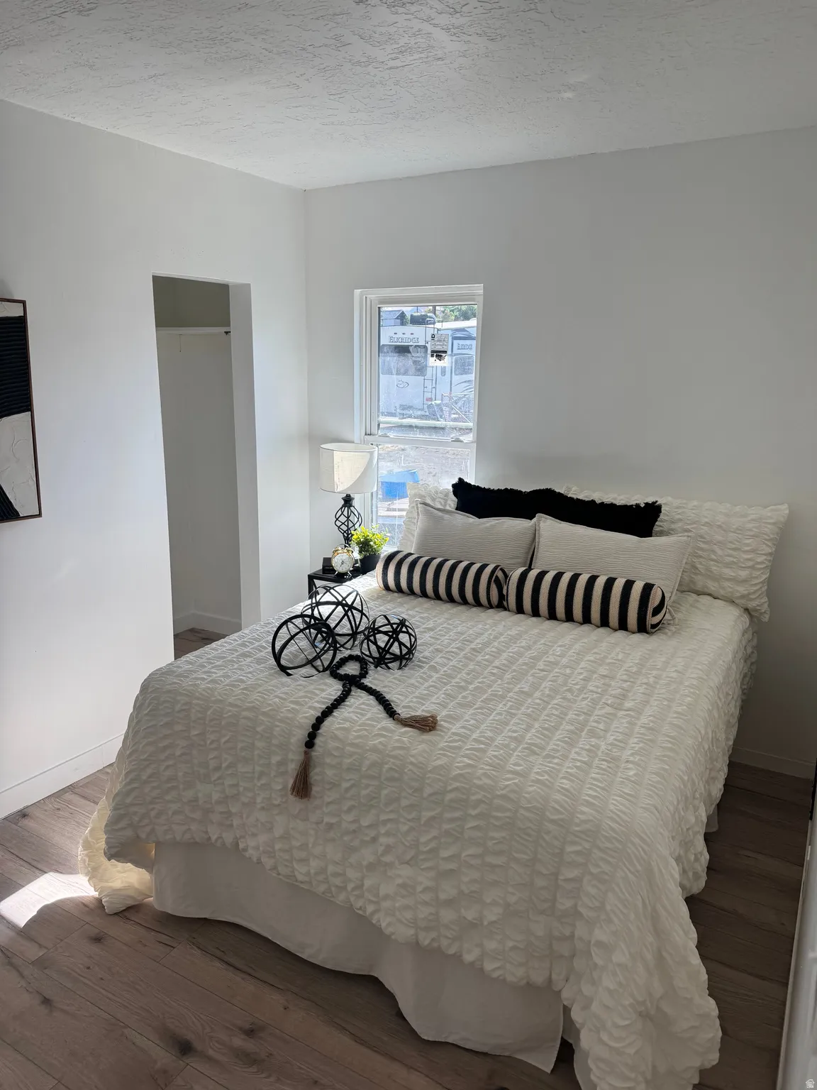 Bright interior space featuring wood-finish flooring, a window with natural light, a neutral color palette, and an open closet area