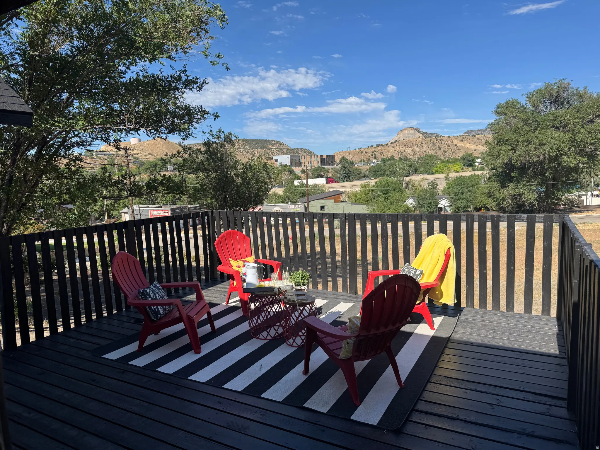Expansive outdoor deck featuring a black wood-finish surface, slatted railing, and a scenic mountain backdrop