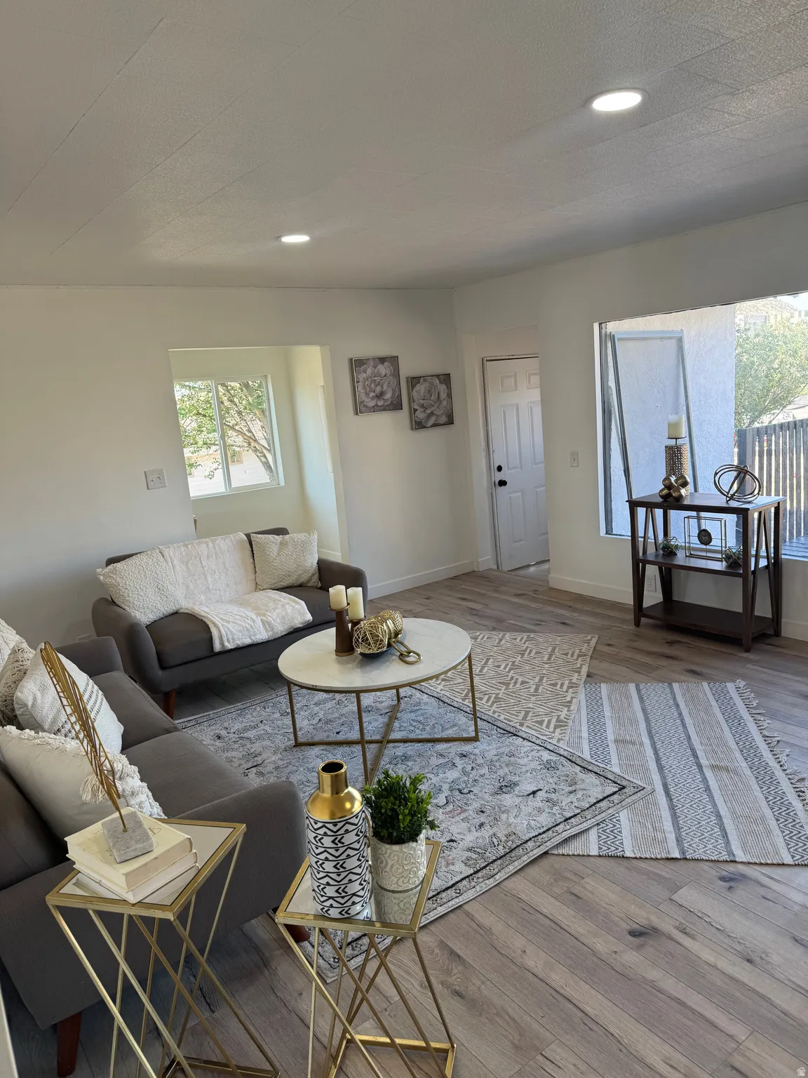 Spacious living area featuring light wood-finish flooring, recessed lighting, and white wall finishes