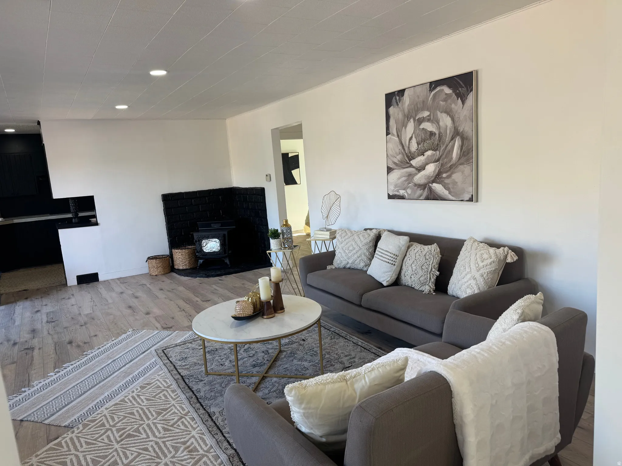 Expansive living area with wood-finish flooring, a black brick fireplace, and recessed lighting