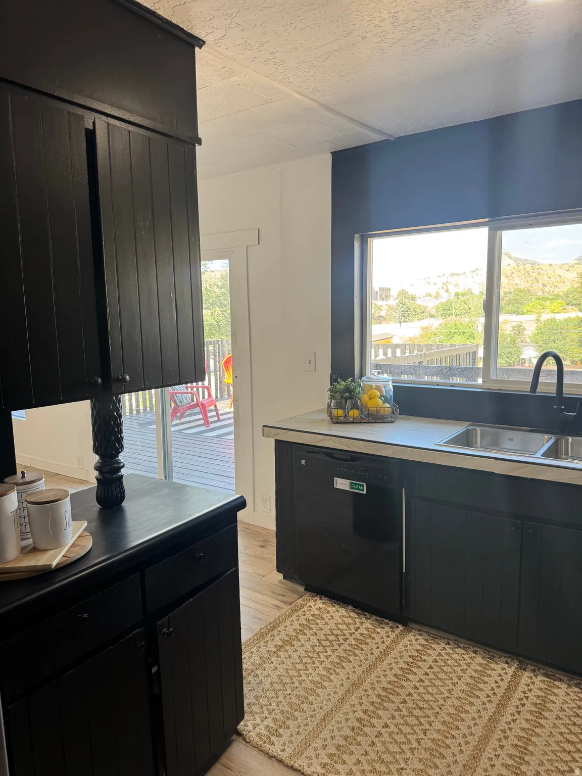 Kitchen featuring black cabinetry, light-toned countertops, stainless steel sink with a matte black faucet, and a black dishwasher