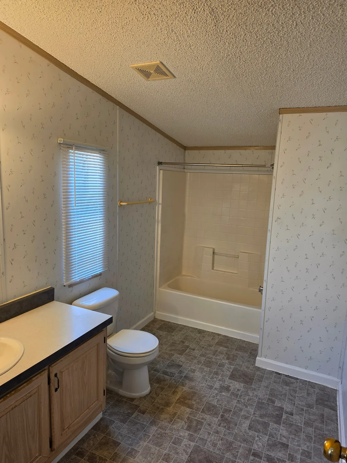 Bathroom featuring a single vanity with wood-finish cabinetry, a toilet, and a bathtub with an integrated shower