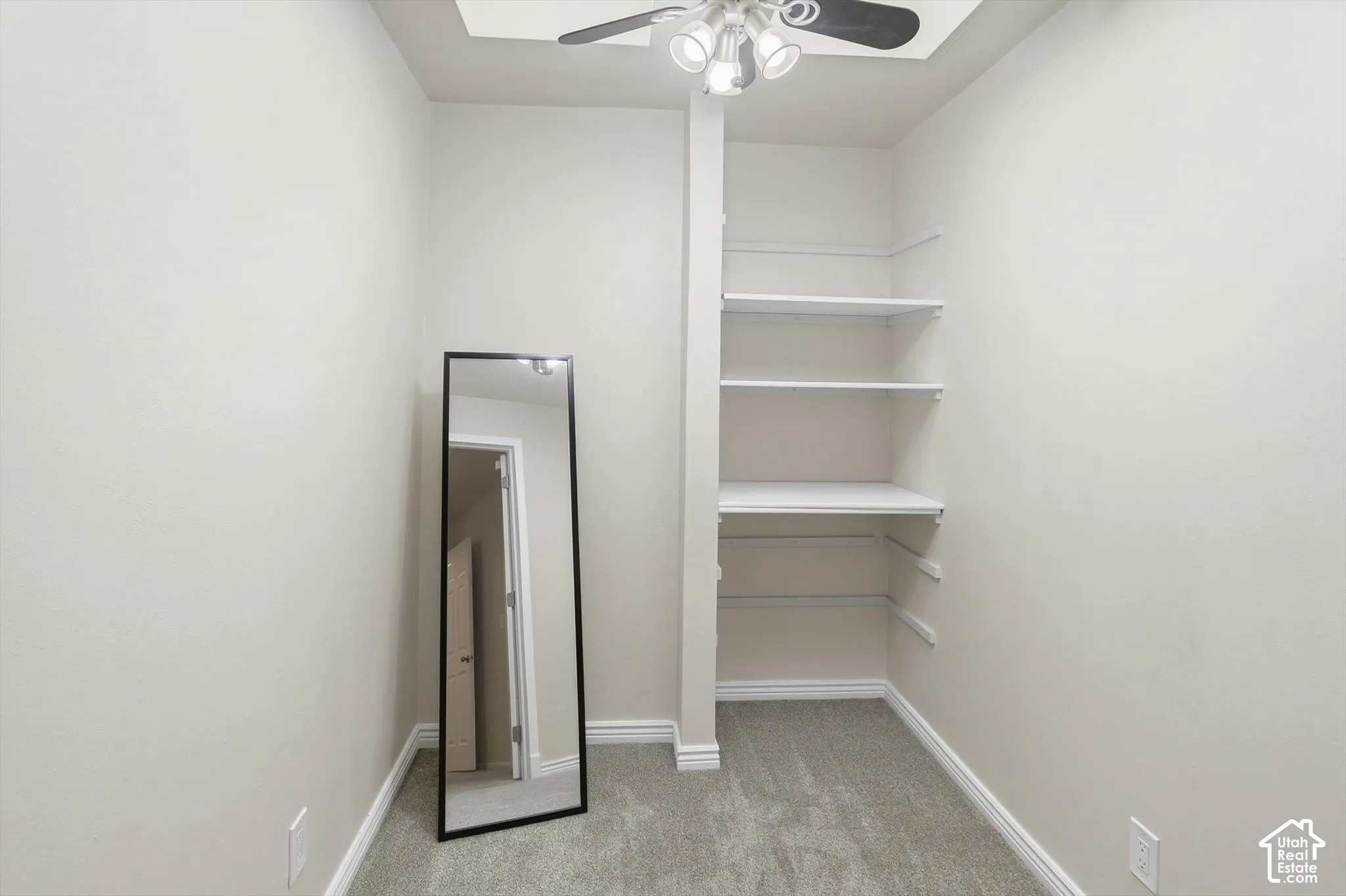 Recessed ceiling fan with integrated lighting, built-in shelving, carpet flooring, and baseboard trim