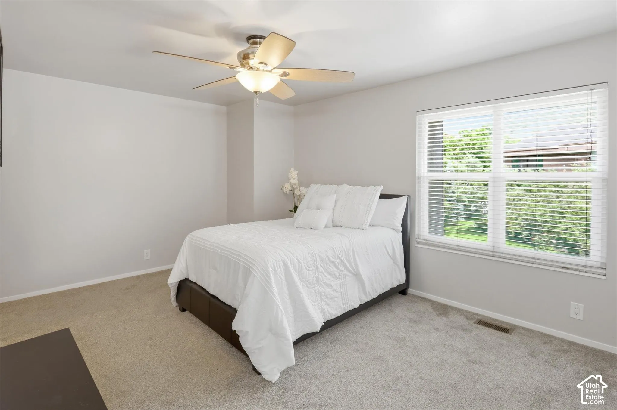 Carpeted room featuring a ceiling fan with integrated lighting, a window with horizontal blinds, and light-toned wall finishes