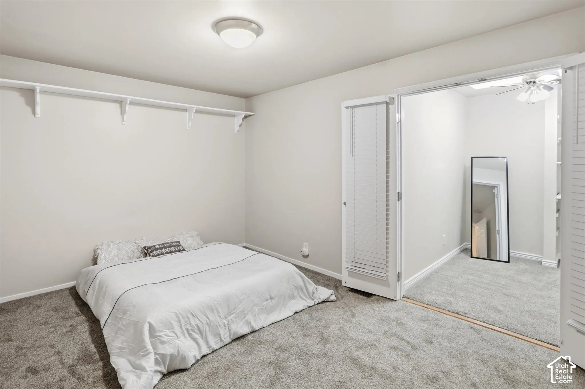 Carpeted room featuring a ceiling-mounted light fixture, white walls, and built-in shelving