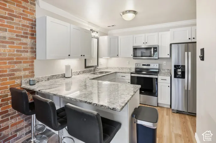 Modern kitchen featuring white cabinetry, light-toned wood-finish flooring, and a stone-look countertop