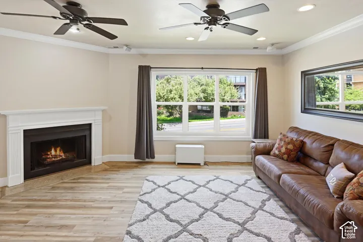 Spacious room featuring wood-finish flooring, a corner fireplace with a white mantel, and a large window