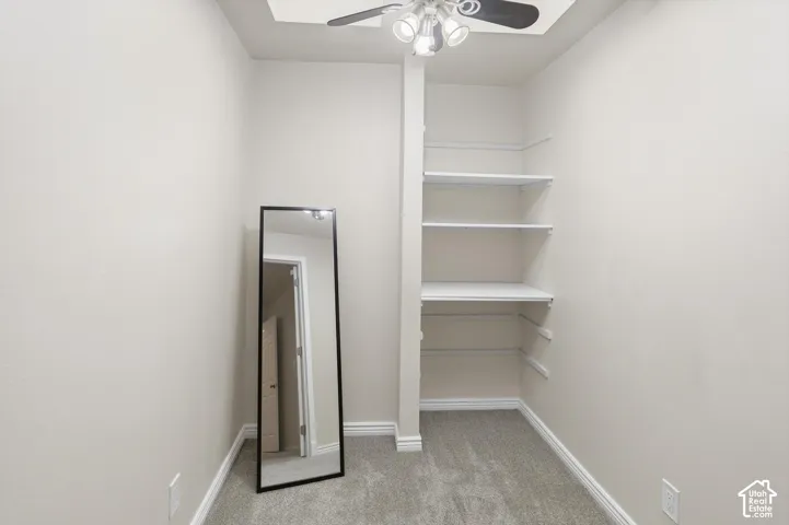 Recessed ceiling fan with integrated lighting, built-in shelving, carpet flooring, and baseboard trim