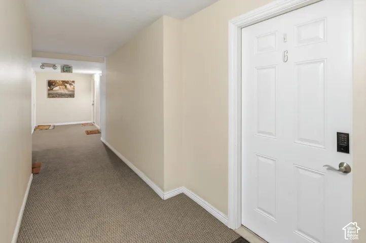 Hallway to garage showing entry door with a digital keypad lock, brushed nickel hardware, and white trim