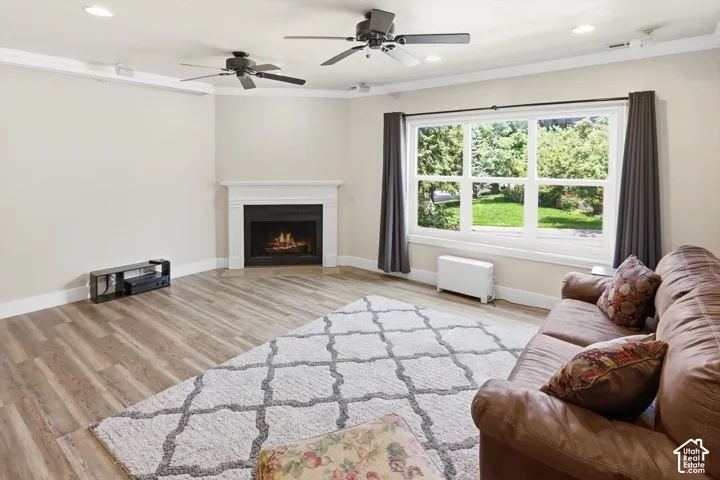 Living area featuring a white mantel fireplace, wood-finish flooring, and multiple ceiling fans