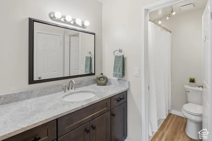 Bathroom featuring a dark wood-finish vanity with a light speckled countertop, an undermount sink, and a framed mirror